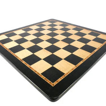 Load image into Gallery viewer, A low-angle perspective shot showing an empty wooden chessboard with bird's-eye maple and black squares set against a clean white background.
