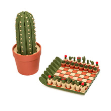 Load image into Gallery viewer, A potted green cactus decorative storage container displayed alongside an unfolded mini chess set featuring potted cactus playing pieces on a checkered board.
