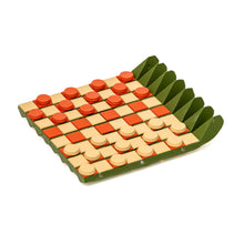 Load image into Gallery viewer, A green flexible game board with a orange and cream checkered pattern, set up for checkers with round disc pieces
