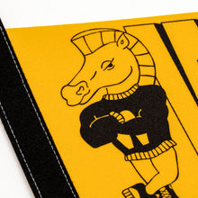 Load image into Gallery viewer, This close-up shows a detailed view of the yellow felt pennant with a black strip stitched along its left edge. It highlights a printed graphic of a cartoon knight chess piece mascot wearing a black sweater with folded arms and a smirking expression.
