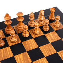 Load image into Gallery viewer, A close-up, angled view of golden-grained olive wood chess pieces set up on a black and olive wood chessboard.
