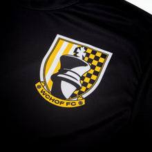 Load image into Gallery viewer, This detailed photo highlights a crest printed on black athletic fabric. The shield features a large king chess piece silhouette in the center, flanked by yellow and white vertical stripes on the left and a yellow and black checkered pattern on the right, all above a banner reading "WCHOF FC".

