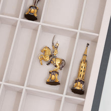 Load image into Gallery viewer, A close-up view of intricate gold and silver ornate chess pieces resting inside the white felt-lined slots of a storage case.

