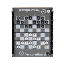 Load image into Gallery viewer, A top-down view of an unfolded VentureBoard mini travel chess set during a game, showing black and white circular chess pieces arranged across its grey-and-black grid.
