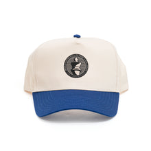 Load image into Gallery viewer, A two-tone baseball cap with an off-white crown and a contrasting blue brim paired with a matching blue top button. Centered on the front panel is a circular black patch featuring a white king chess piece icon encircled by the text "WORLD CHESS HALL OF FAME &amp; GALLERIES SAINT LOUIS, MISSOURI".
