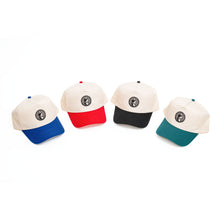 Load image into Gallery viewer, This shows four two-tone baseball cap, each featuring an off-white crown and a circular chest-piece logo centered on the front. The caps are distinguished by their brightly contrasting brims and matching top buttons in blue, red, black, and teal.
