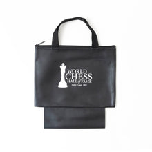 Load image into Gallery viewer, A black zippered chess piece bag with black woven handles and a folded bottom pouch, featuring the white "World Chess Hall of Fame, Saint Louis, MO" king logo printed on the front.
