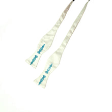 Load image into Gallery viewer, This is an untied off-white bow tie decorated with a vivid, bright turquoise print of detailed, ornate chess pieces running vertically down the paddles.
