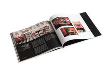 Load image into Gallery viewer, An open book spread featuring interior photography of a chess-themed diner and exhibition displays against dark pages.
