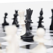 Load image into Gallery viewer, A close-up view of interlocked white and black chess pieces standing coupled together on a checkered board during gameplay.
