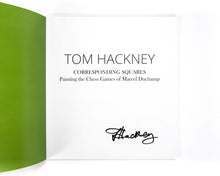 Load image into Gallery viewer, The title page of the Tom Hackney: Corresponding Squares exhibition catalog displaying the book title and author name in clean black serif and sans-serif fonts, featuring a handwritten signature at the bottom right.
